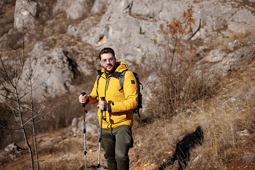 Portrait of young male hiker standing and looking at camera while hiking on rocky mountain alone