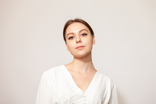 Studio portrait of a young white woman in a white blouse against  a white background