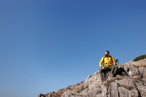 Young man sitting and resting from hiking on rocky mountain