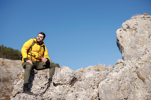 Young man sitting and resting from hiking on rocky mountain