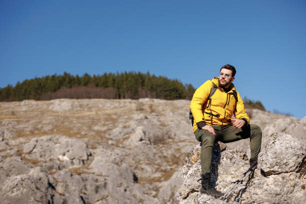 istock Young man sitting and resting from hiking on rocky mountain 1472245604