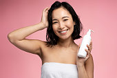 Asian woman holding hair conditioner before applying