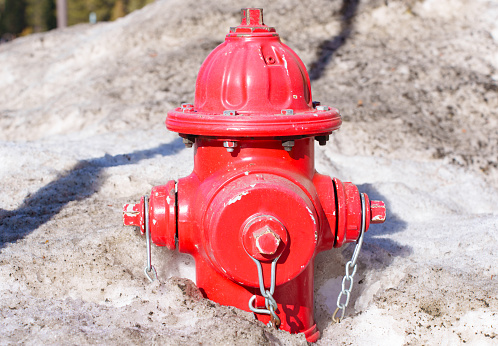 Red fire hydrant half buried in dirty snow. Fire safety and hydrant access in winter.