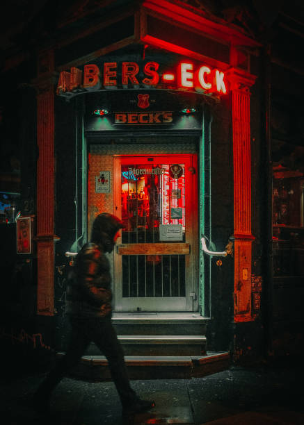 One Person walking down the street in front of the famous hamburger pub. Red and green colors and moody dark atmosphere. Picture was shoot in the late evening.