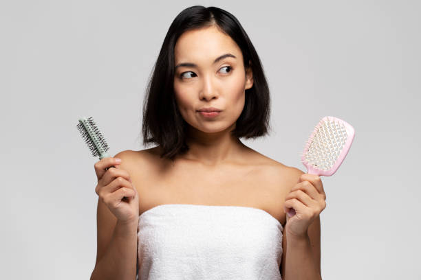 istock Pensive woman pondering with two hair combs while posing 1472247129
