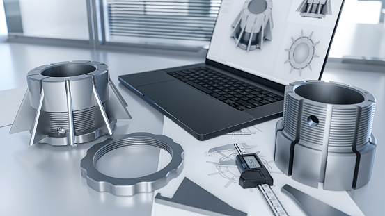 Engineer's desk while testing the quality of thread and fit mechanical components, using a caliper and a laptop with a CAD program