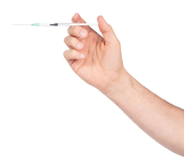 istock New syringe in adult hand on white background 1472247904