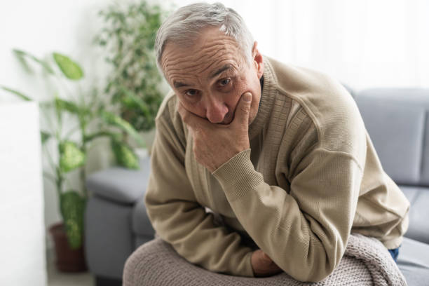 istock Frustrated unhappy middle aged mature man sitting on sofa, feeling depressed alone at home. Confused senior retired grandfather worrying about difficult life decision, copy space, old people solitude 1472248343