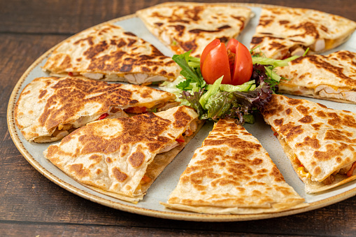 Mexican quesadilla with chicken, cheese and peppers on wooden table