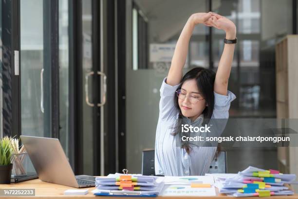 Asian Businesswoman Feel Tired From Hard Work Thus Doing Arm Stretching Posture To Relax Body Tired Asia Woman Stretching Her Hands While Working In Office Stock Photo - Download Image Now