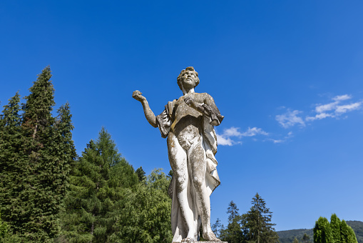 Sinaia - Romania. July 15, 2022. Daylight view from bottom to marble statue of Greek poet reciting poetry in garden of Peles Castle