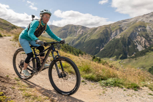 istock Female mountain biker taking speed riding down the mountain on a curve 1472258269