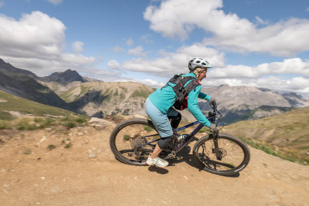 istock Female mountain biker taking speed riding down the mountain on a curve 1472259391