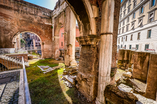 A glimpse of the ancient remains of the Roman temple of Portico d'Ottavia in the Jewish quarter of Rome, or Roman Ghetto, in the historic heart of the Eternal City. The iconic Jewish neighborhood, the oldest ghetto in Europe, is famous for the presence of hidden alleys and small squares, where it is easy to find restaurants of Italian and Jewish cuisine, and remarkable Roman archaeological remains. The Ghetto of Rome is located in one of the oldest districts of the city between the Campidoglio, or Roman Capitol, and the River Tiber. In 1980 the historic center of Rome was declared a World Heritage Site by Unesco. Super wide angle image in high definition quality.
