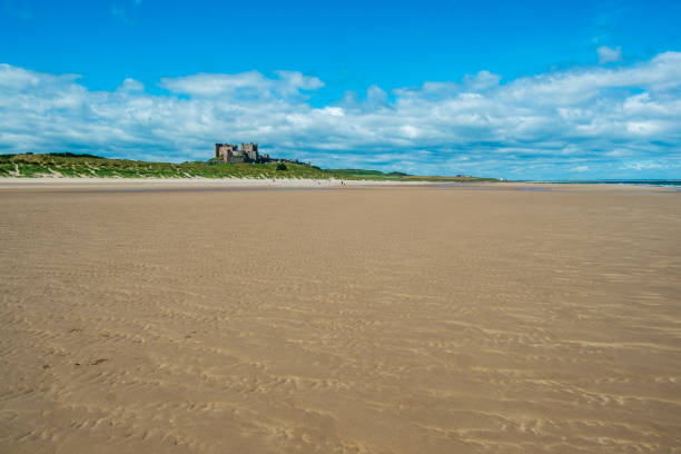 Bamburgh beach 4th July 2022 - Bamburgh, UK: Looking north west to historic Bamburgh Castle on the horizon above Bamburgh beach, Northumberland, UK Bamburgh stock pictures, royalty-free photos & images