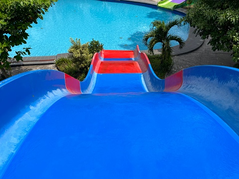 Colorful water slide towards the swimming pool in the aqua park on a sunny day.