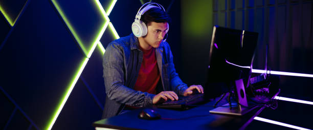 istock Young man playing an online video game on a pc, with a headset for communication with other gamers 1472261320