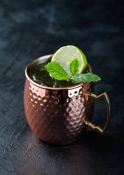 istock Moscow mule cocktail in a copper mug with lime and mint on dark background 1472262371