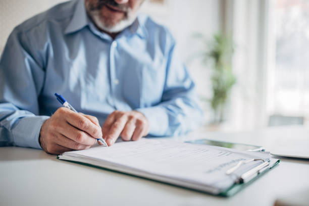 istock A man signs a paper document with a pen 1472262853
