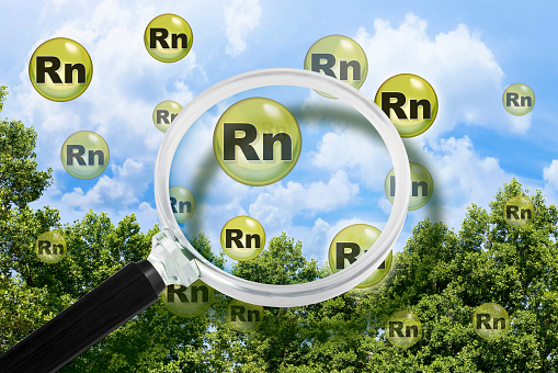 Dangerous Radon gas Rn molecules that come out of the ground and pollute the air - concept against a strees background and and magnifying glass