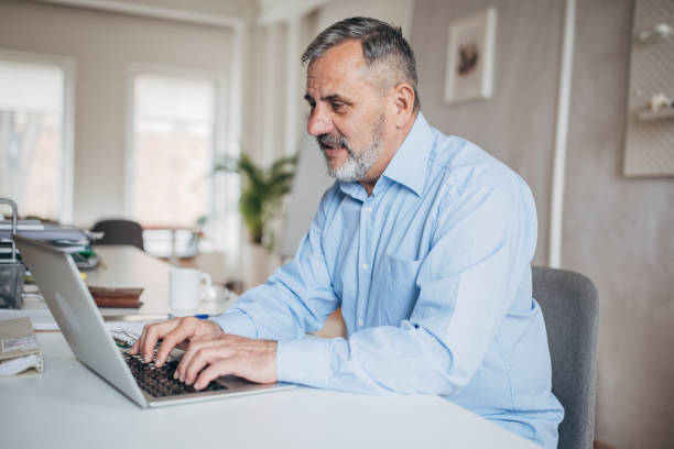 istock Senior businessman using laptop in office 1472263200