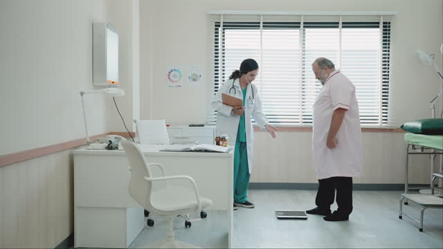 After managing nutrition, a Latin female nutritionist uses a weighing equipment to monitor the patient's weight and fat. An Asian man receives a health check from medical specialists.
