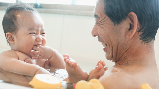 Asian Grandchild and Grandfather taking a bath at home.