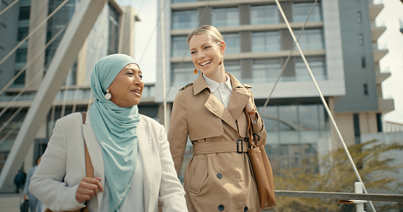 Business women, teamwork communication and city with diversity of corporate lawyer staff outdoor. Hijab, happy conversation and walking of management staff laughing together feeling happiness