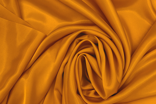 Mockup Abstract silk gold background. Luxurious smooth elegant wavy fabric. Can be used for your design. Top View, Copy Space