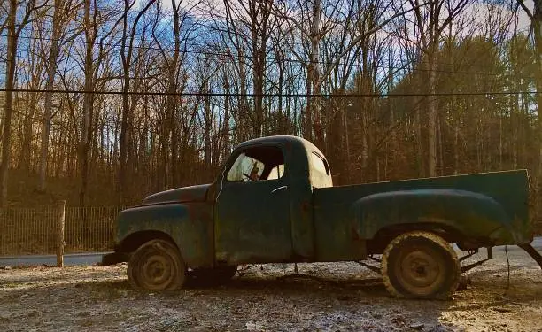 A broke windshield on an abandoned vintage Studebaker truck which is stuck in mud
