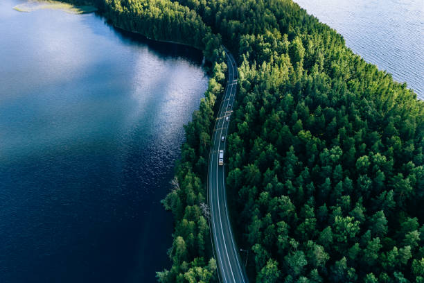 aerial view of road in green woods and blue lakes water in finland - blue fin imagens e fotografias de stock