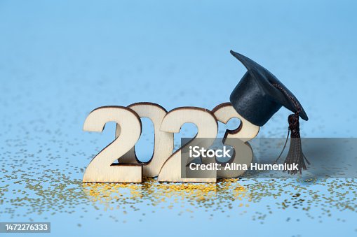 istock Class of 2023 concept. Wooden number 2023 with graduated cap on colored background 1472276333