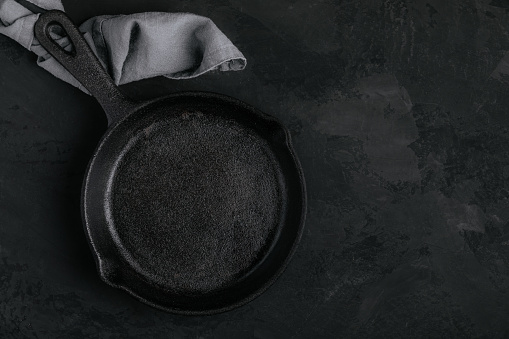 Roast Pan. Empty cast iron frying pan on dark stone background, top view, copy space.