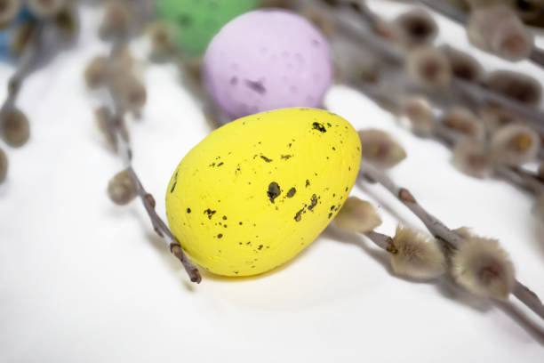 istock Colored eggs lie next to willow branches on a white background. Among the willow branches lie painted eggs for Easter. Festive decor for Easter with quail eggs, 1472277885