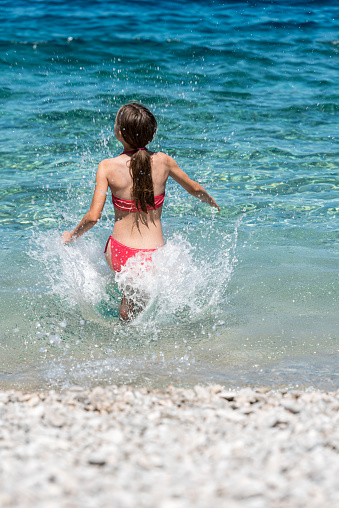 Teenage Girl on Summer Holiday Enjoy Running in the Transparent Waters of Mediterranean Sea, Cres Island, Croatia