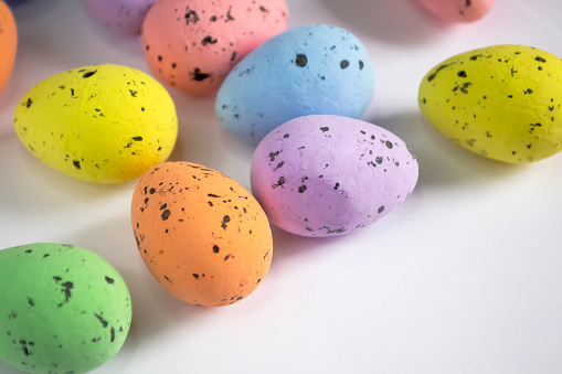 Decorated eggs for Easter lie on a white background. Decorations for Easter - symbolism - colored eggs. Quail eggs at the point are painted in different colors.