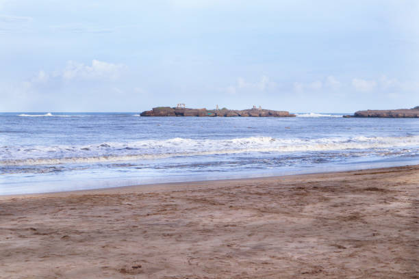 wunderschön der sandstrand von nagaon mit seinem blauen wasser in der ferne in diu, gujarat, indien. das braune schlammige wasser und mit einem sandstrand. blick auf arabisch. der indische ozean und die ikonische schrift von diu - horizontal landscape coastline gujarat stock-fotos und bilder