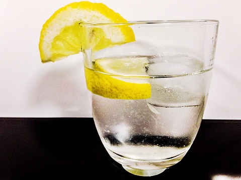 Glass of fresh water with lemon slices, in front of a white background