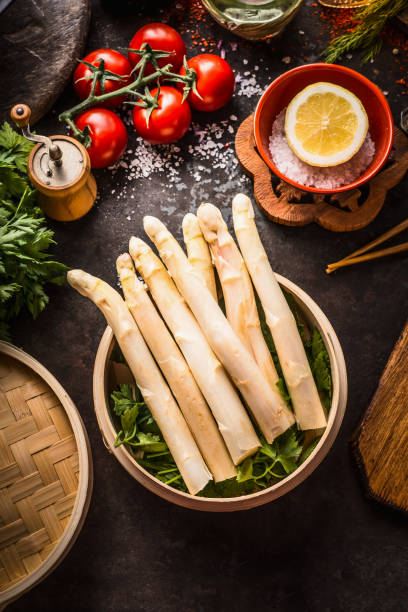 istock Asparagus in bamboo steamer on dark rustic kitchen table with ingredients and chopsticks, top view 1472279693