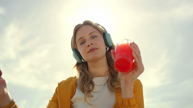 Music, headphones and woman portrait with phone and juice while dancing for sunset sky travel. Model person with smartphone and smoothie drink on summer vacation while streaming podcast on internet