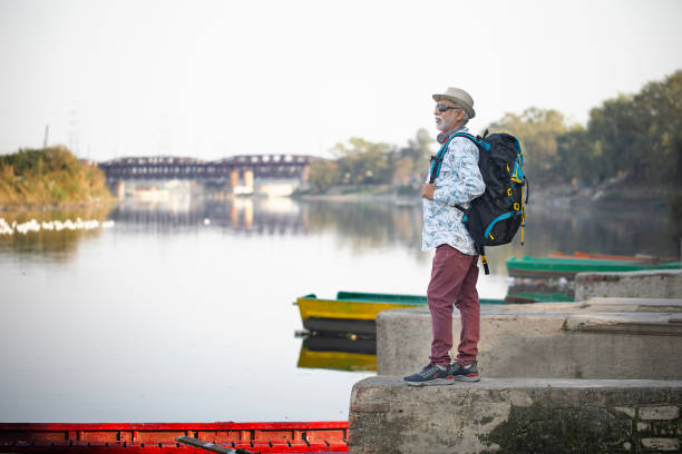 istock Old man admiring view standing on concrete platform by lake 1472280711