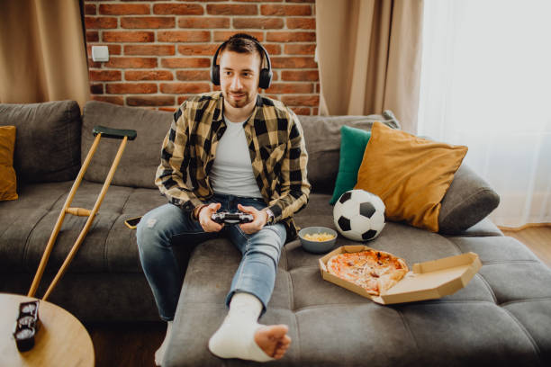 istock High-angle view of a young man gaming at home while resting during the injury 1472280897