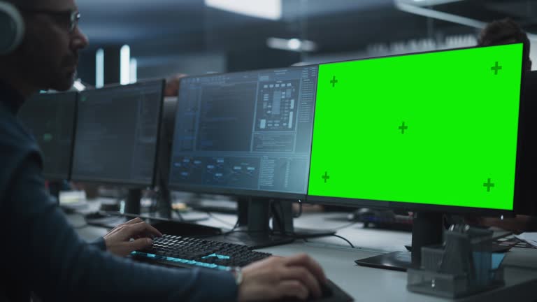 Close Up of a Software Developer Working on a Desktop Computer with Green Screen Mock Up Display. Specialist Typing on Keyboard, Coding and Implementing a New Technical Feature, Working in an Agency