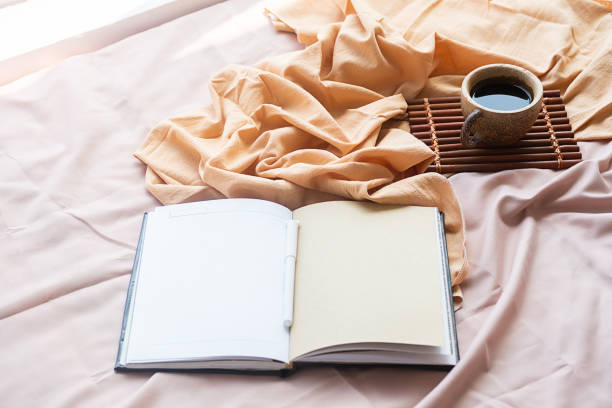 istock Coffee cup, bamboo tray and open notebook on bed. Good springtime morning. 1472285011