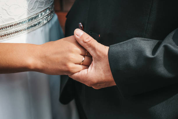 Close-up photo of the hands of the bride and groom, decorated with wedding rings. The beauty of their intertwined fingers. Rings on the hand of the bride and groom stock photo