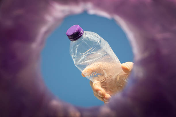 Throwing away a plastic bottle into a bin for recycling low angle view