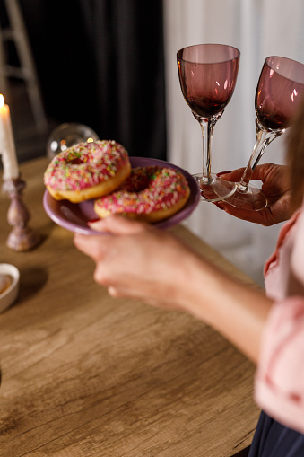 Close up shot of unrecognizable young woman serving doughnuts and wineglasses on a table when setting up for a celebratory event.