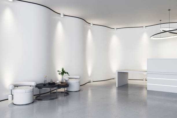 istock Perspective view on spacious reception area in light interior design office with armchairs on wall background and desk on glossy concrete floor. 3D rendering 1472287144