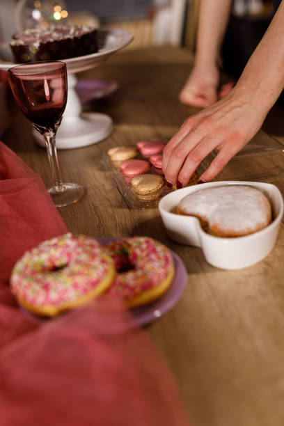 istock Young woman arranging heart shaped macaroons around a cute small cake 1472287784