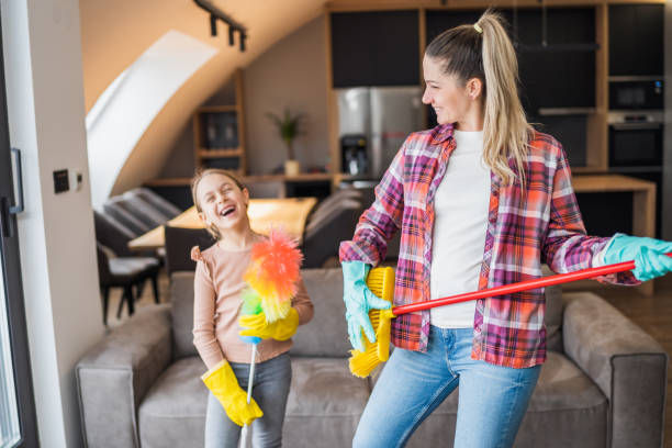 istock Mother and daughter having fun while cleaning  house 1472289602